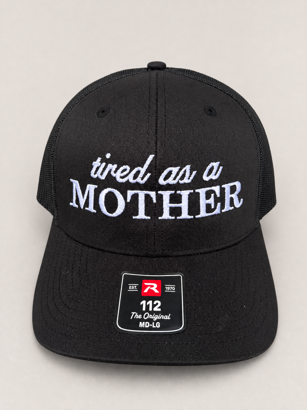 Black trucker cap displaying 'tired as a mother' embroidery.